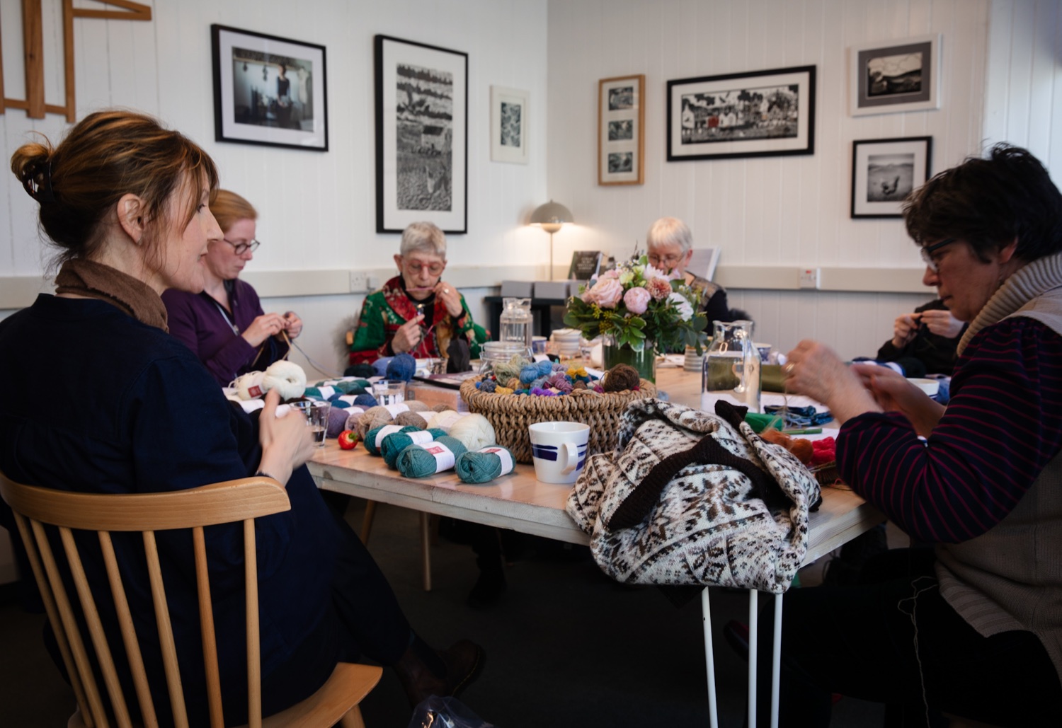 Women sitting around a large table with yarn during a Shetland Knitting Tour